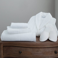 Eastman Heritage spa set including a white plush bathrobe and stacked towels offering layers of natural comfort for an elegant and luxury lifestyle.
